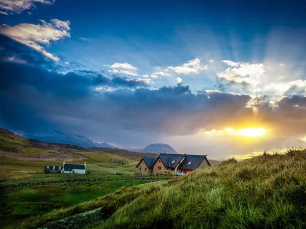 a house in the middle of a field with the sunset at Skipaflotta in Rhiconich