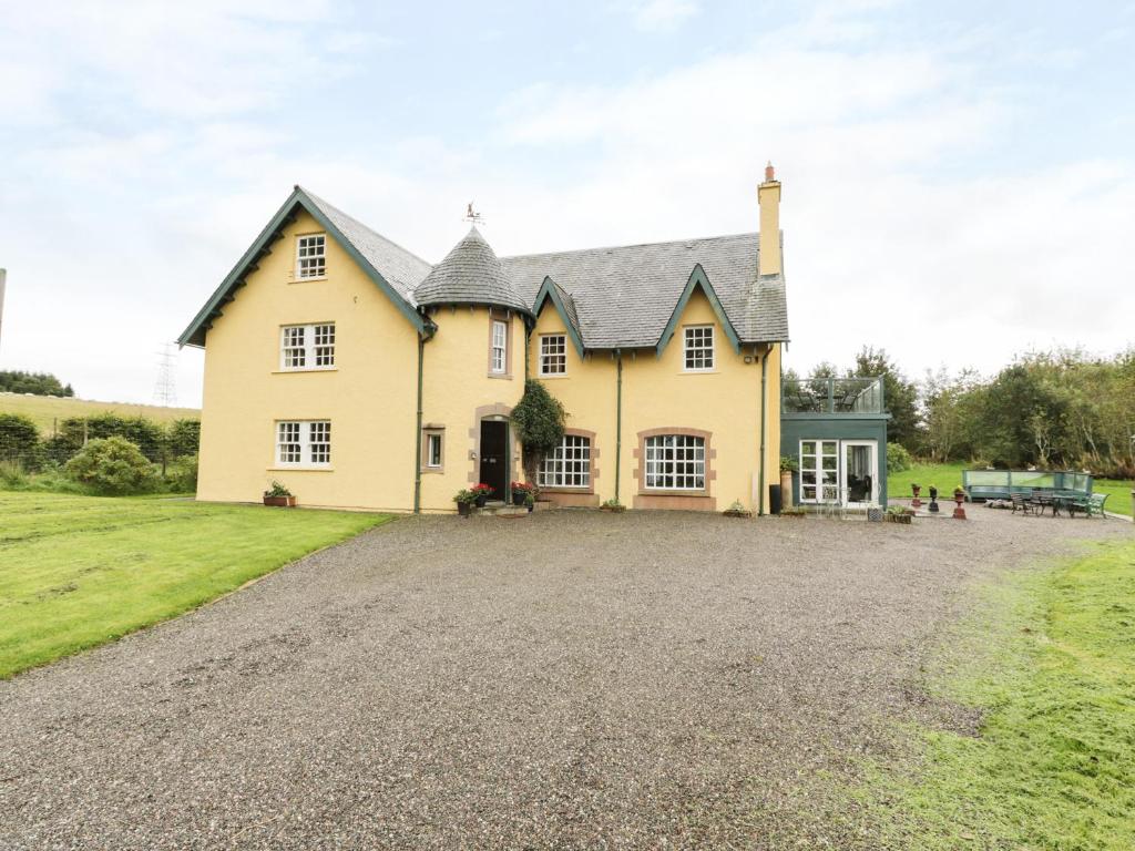 a large yellow house with a gravel driveway at Tulchan Lodge in Buchanty