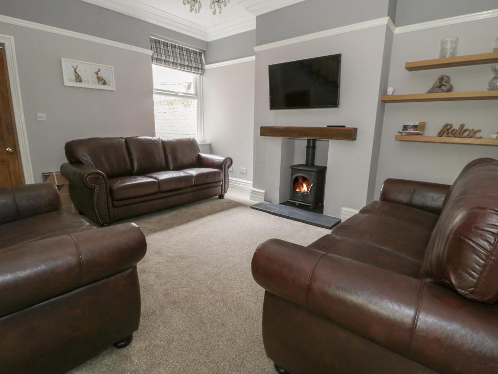 a living room with two leather couches and a fireplace at Dumbuie in Haltwhistle