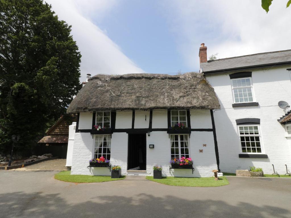 an old white house with a thatched roof at Eightlands in Hampton Bishop