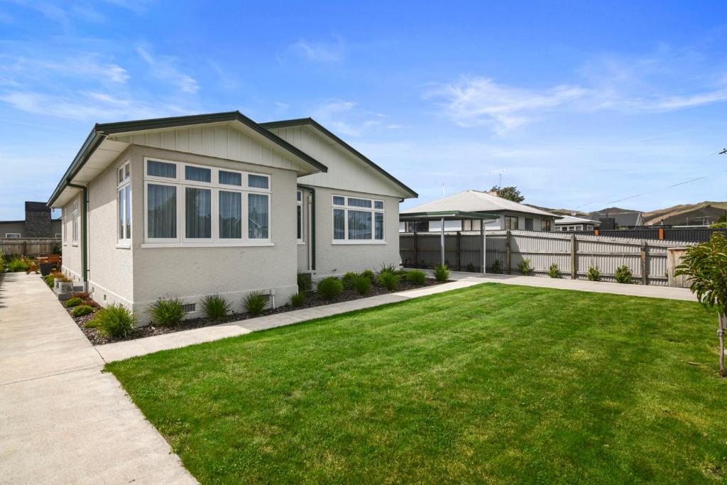 a house with a green lawn in front of it at Bliss on Barratt - Blenheim Holiday Home in Blenheim