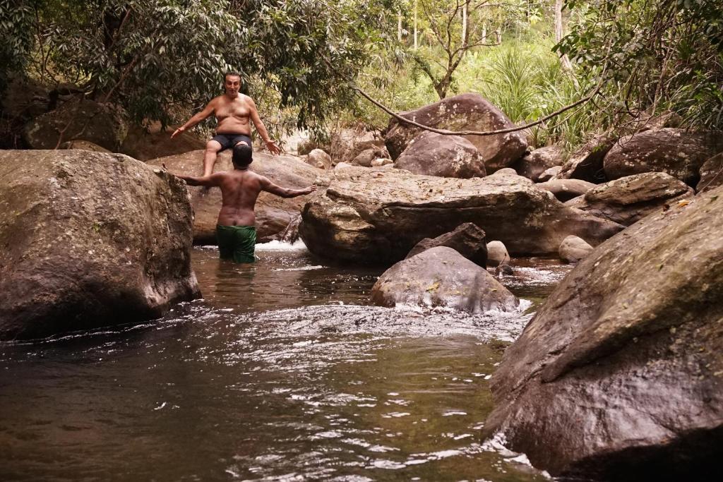 dos hombres parados en el agua en un río en Retiyagama Eco Resort, en Teldeniya