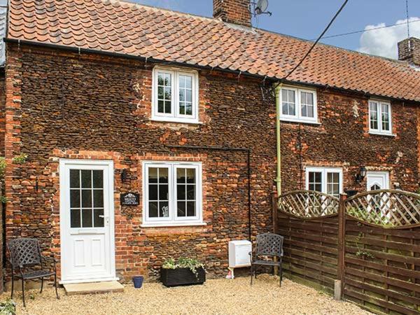 a brick house with chairs in front of it at Meggie's Cottage in Dersingham