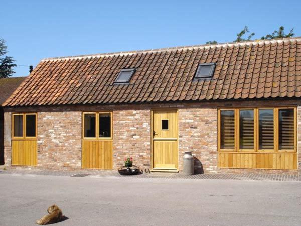 a brick building with yellow doors and a roof at Ginny's Barn in Askham