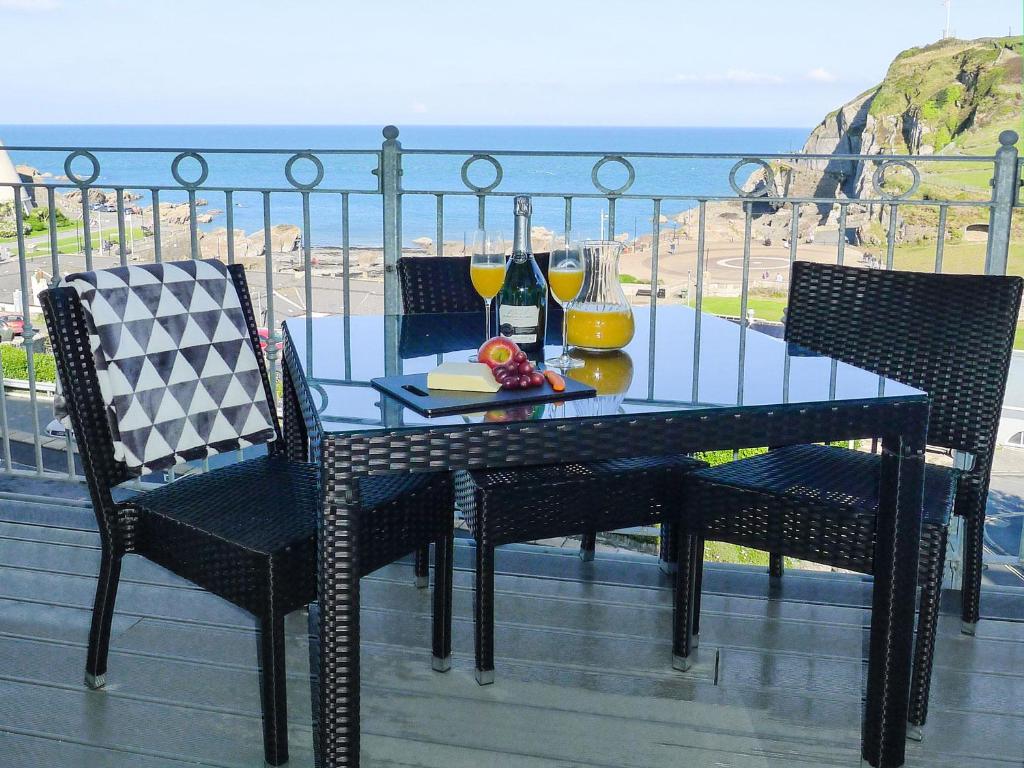 een tafel en stoelen op een balkon met uitzicht op de oceaan bij 5 Arlington Villas in Ilfracombe