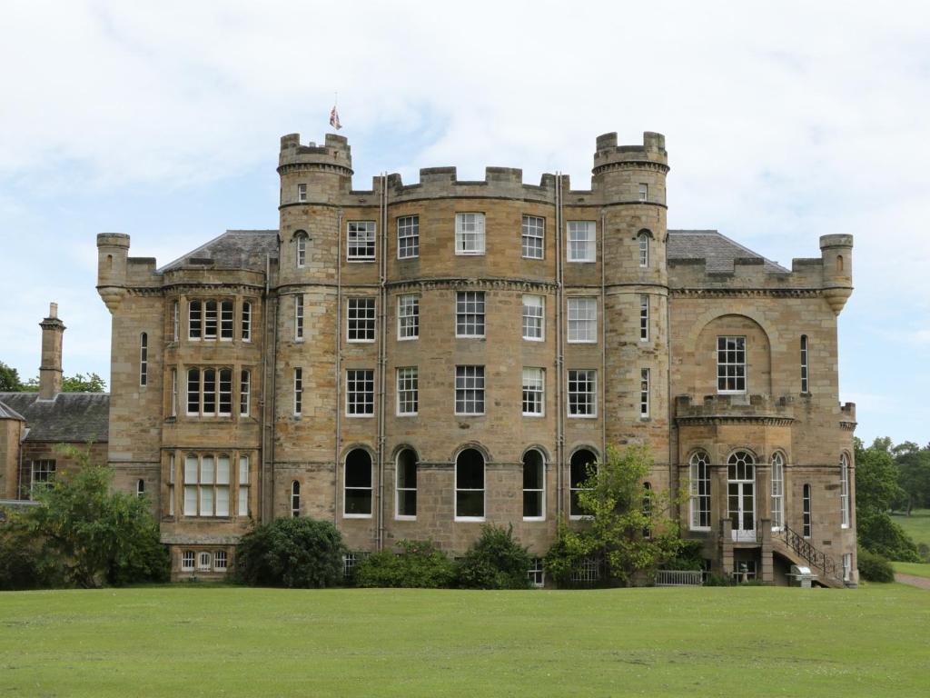 an old castle with a grass field in front at Housekeeper's Rooms in Pathhead