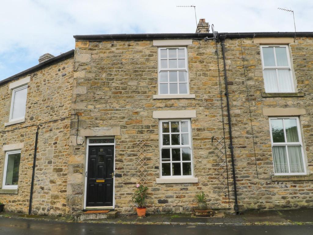 uma antiga casa de pedra com janelas brancas e uma porta preta em Whitfield Cottage 21 Silver Street em Wolsingham