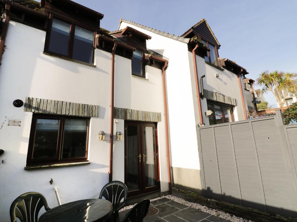 ein weißes Haus mit einem Tisch und Stühlen davor in der Unterkunft Gull Cottage in Padstow