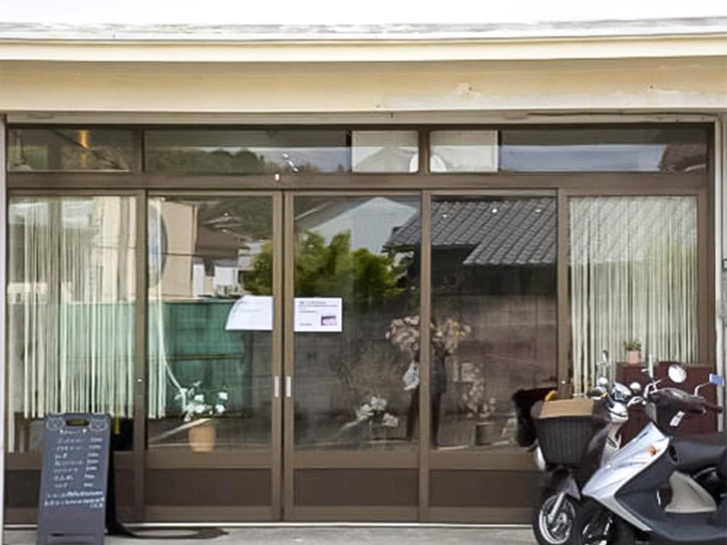 Kamitondacho的住宿－Guest Cafe Kuchikumano，停在大楼前的摩托车