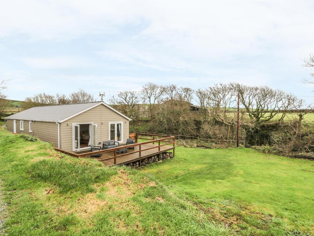 a smallshed on a grassy field with a house at Nant Y Felin Lodge in Aberdaron