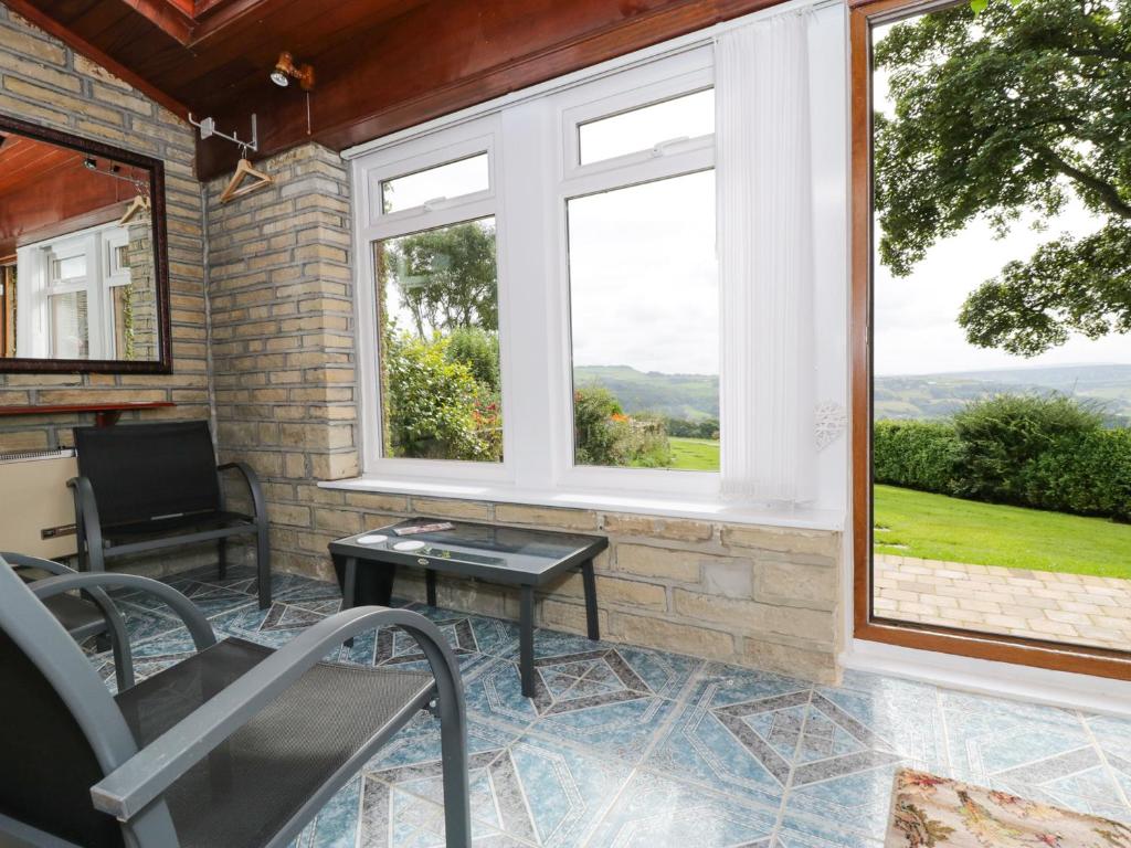 a screened in porch with two windows and a table at Upper Highlees Farm in Luddenden Foot