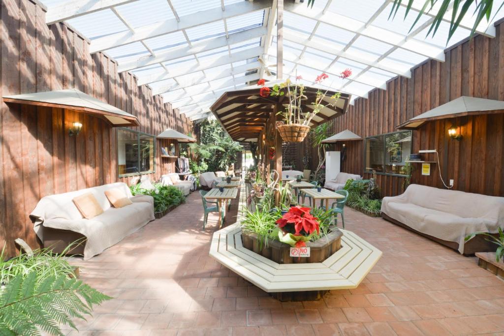 a patio with a conservatory with couches and tables at Wilderness Backpackers in Haast