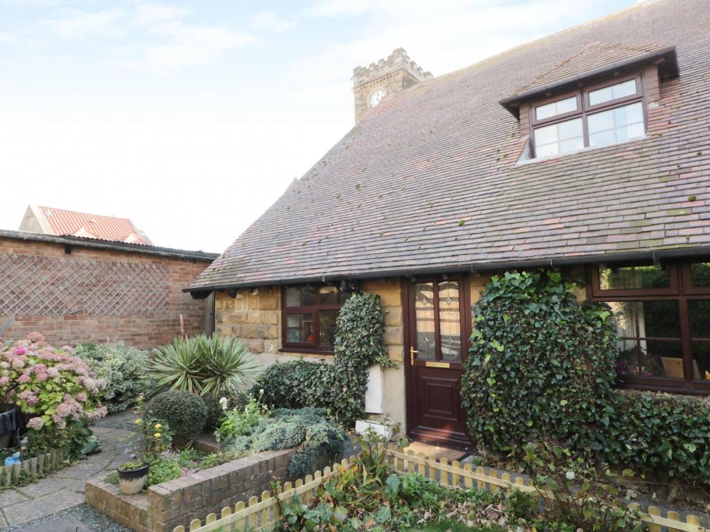 una casa antigua con un jardín delante de ella en Glebe Hall Apartment en Marske-by-the-Sea