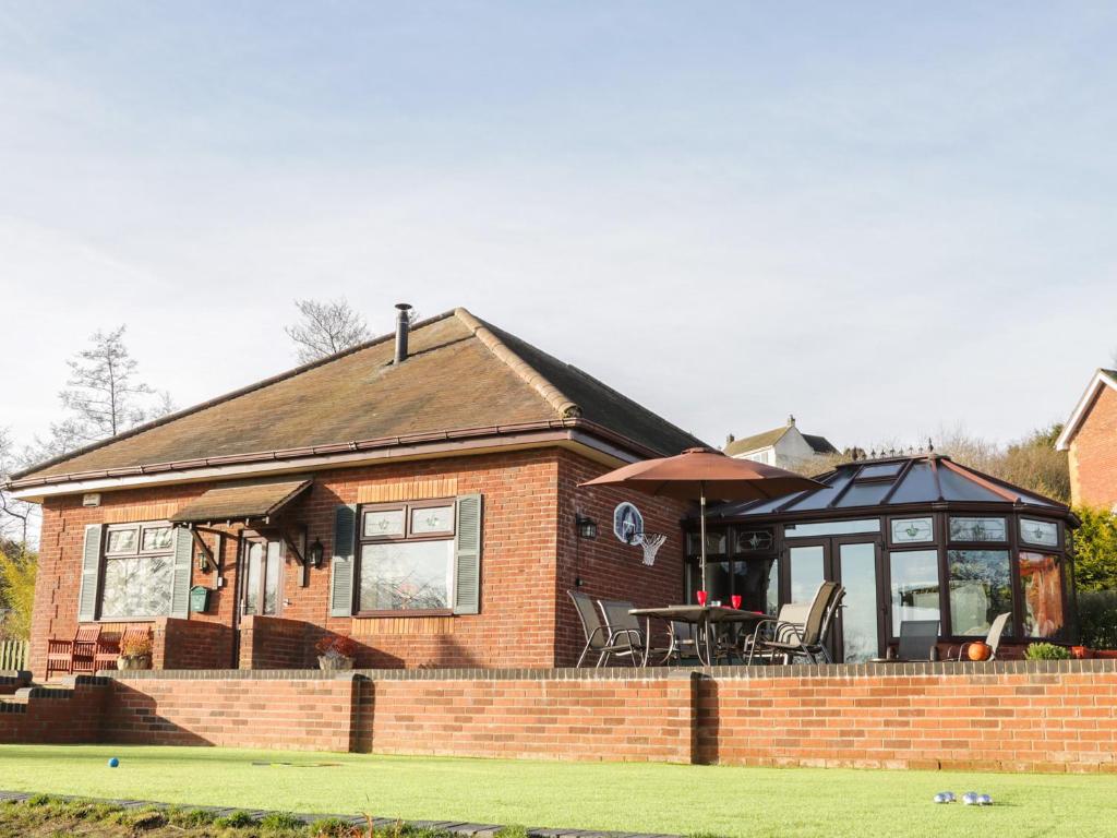 een klein bakstenen huis met een tafel en een paraplu bij Wrens Nest in Coreley