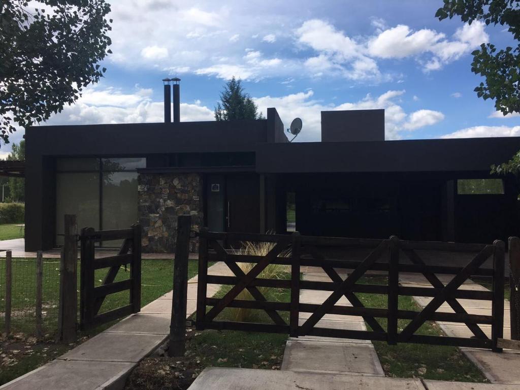 a black house with a wooden fence in front of it at Casa La Herradura- Valle de Uco in Tunuyán