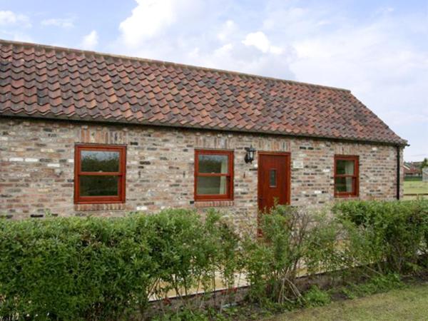 ein Backsteinhaus mit roten Fenstern und einem Zaun in der Unterkunft Lodge Cottage in York