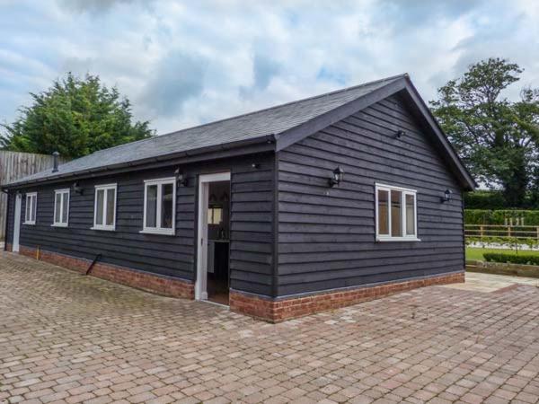 - un petit bâtiment noir avec une porte et des fenêtres dans l'établissement Willow Lodge, à Canterbury