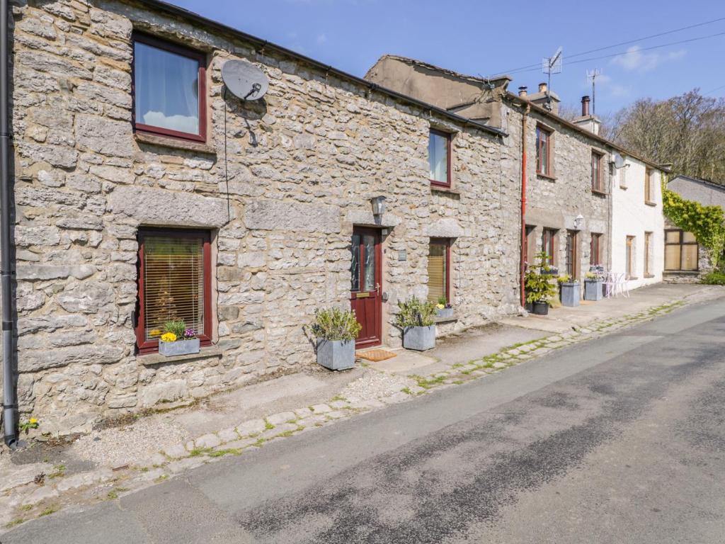 a stone house with potted plants on a street at Rosemary Cottage in Carnforth