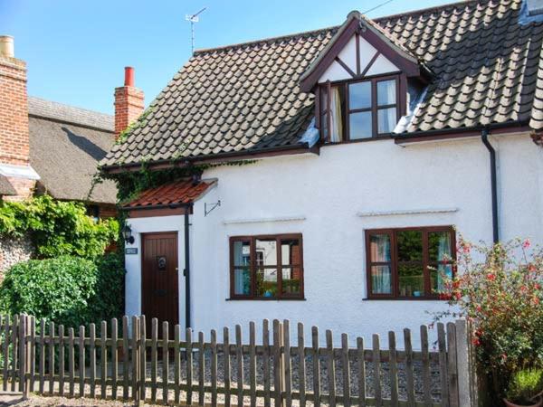 a white house with a fence in front of it at Kingsley Cottage in Hickling