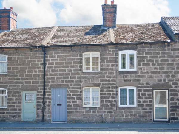 un edificio in mattoni con porta blu e finestre di Bobbin Cottage a Matlock