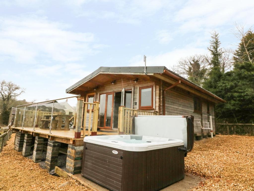 ein kleines Haus mit einem Whirlpool auf einer Terrasse in der Unterkunft The Cabin in Garnant