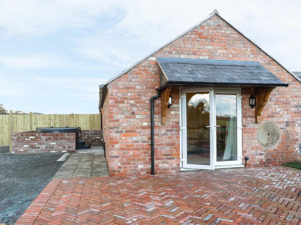 a small brick house with a white door at Millstone Cottage in Westbury