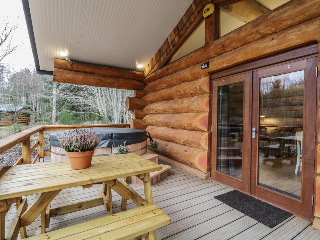 a wooden deck with a picnic table and a sliding glass door at Moorhen Lodge in Inverness