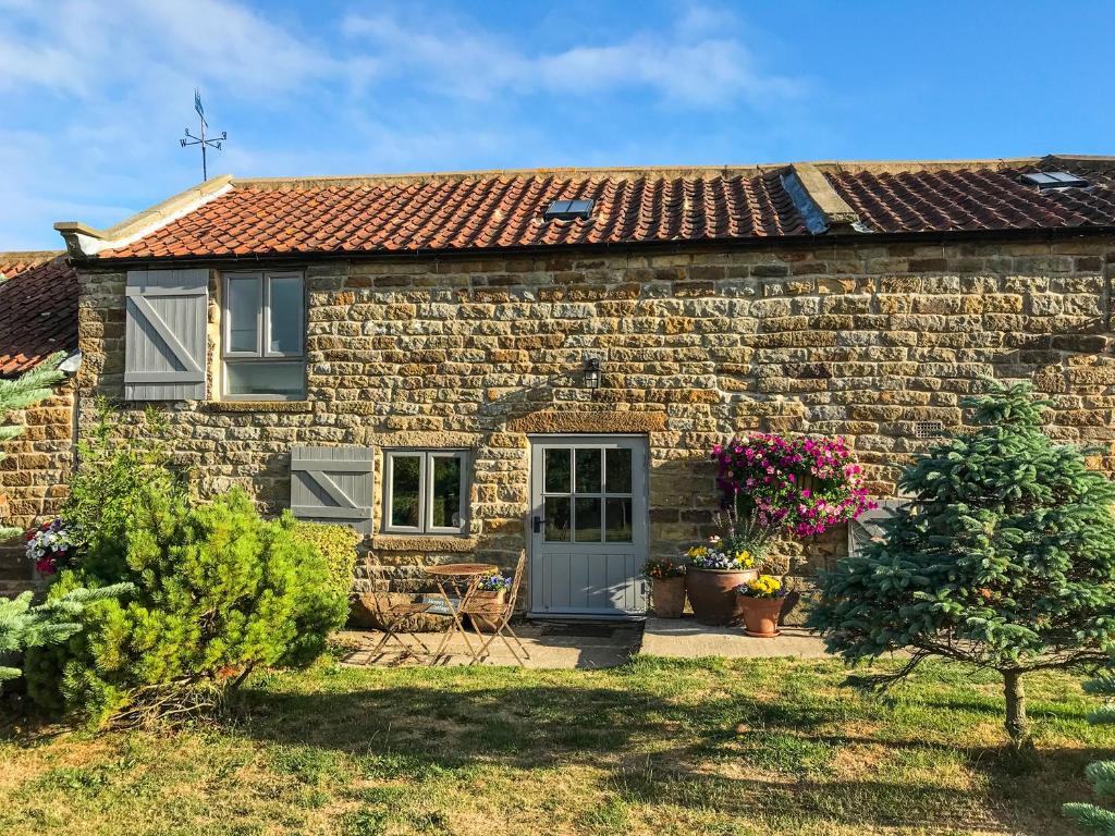 a stone cottage with a blue door and flowers at Honey Bee Cottage in Scarborough