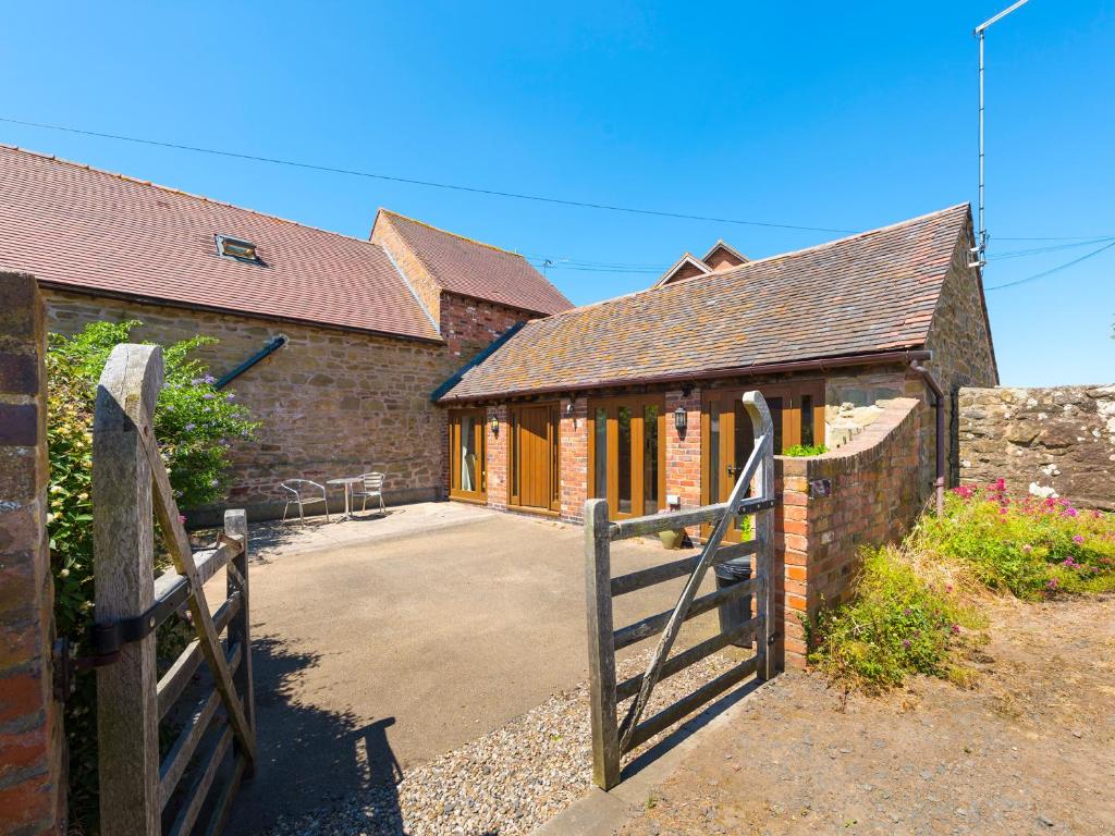 eine Scheune mit einem Holztor und einem Haus in der Unterkunft The Byre in Highley