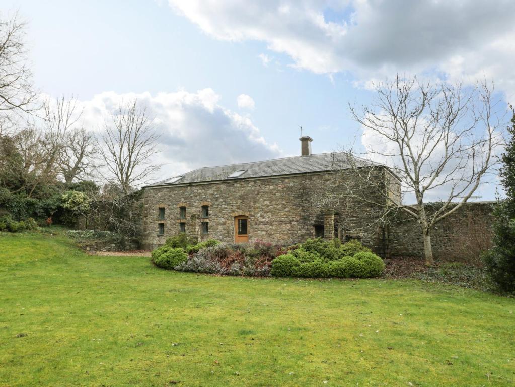 an old stone house with a grass yard at The Coach House in Abergavenny