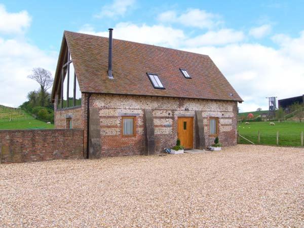 a small brick building with a brown door in a field at Shepherd's Hut in Blandford Forum