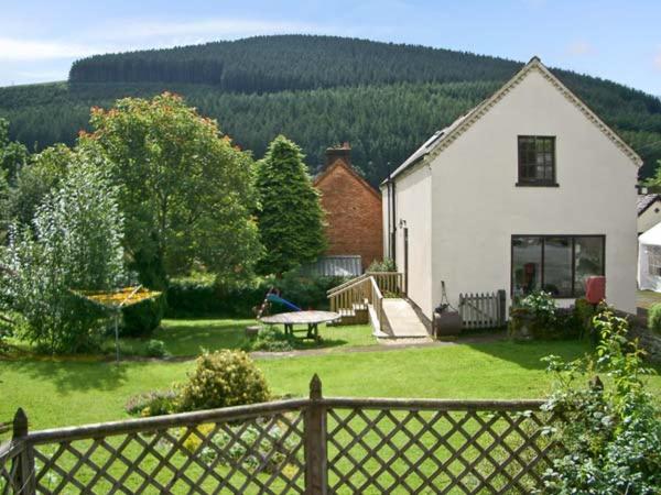 a yard with a white house and a picnic table at Tailor's Cottage in Abbey-Cwmhir