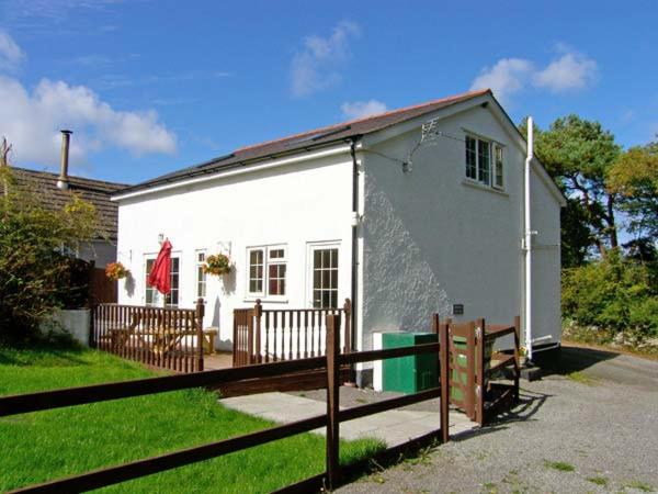ein weißes Haus mit einem Holzzaun davor in der Unterkunft Farmhouse Cottage in Pentraeth