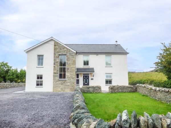 a white house with a stone fence in front of it at Chapel House in Llantrisant