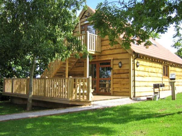 a large wooden cabin with a porch and a deck at Ash Lodge in Watchet