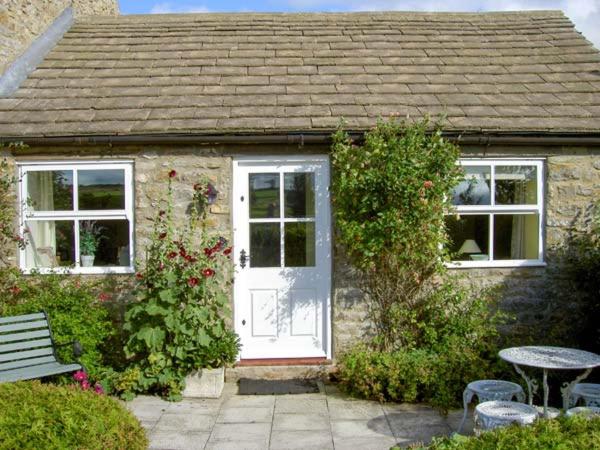 a small house with a white door and a table at Curlew Cottage in Barnard Castle