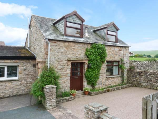 a brick house with a door and ivy at Mews Cottage in Penrith