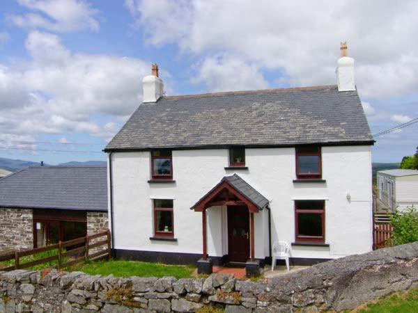 a white house with a stone fence in front of it at The Old Farmhouse in Llanrwst