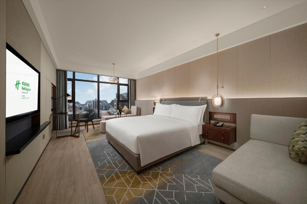 um quarto com uma cama, uma televisão e um sofá em Holiday Inn Changchun Jingyue, an IHG Hotel em Changchun