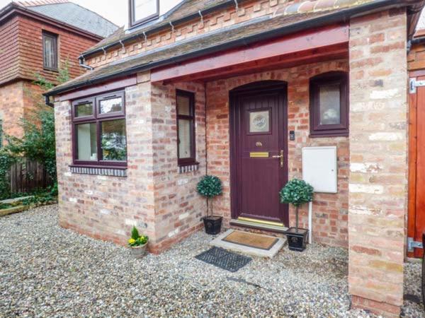 uma casa de tijolos com uma porta e dois vasos de plantas em Beacon Cottage em Great Malvern