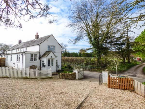 a white house with a fence in front of it at The Old Smithy in Bridport