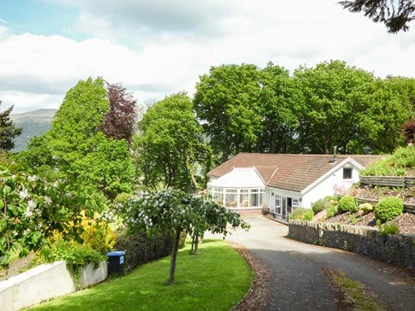 a white house with a garden and a driveway at Treetops in Abergavenny