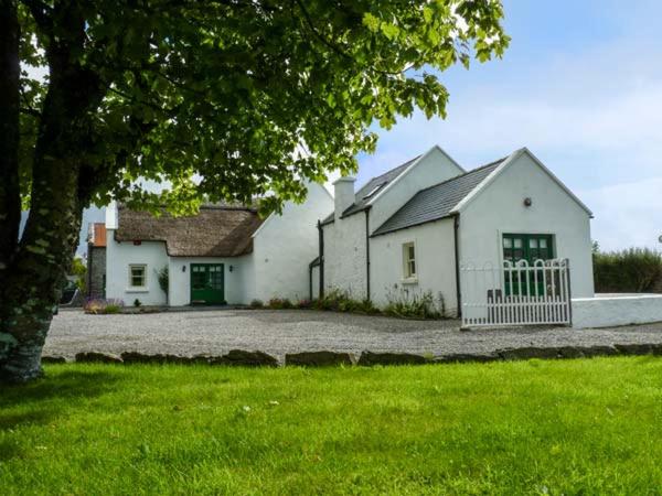 a white house with a white fence in a yard at Annie's Cottage in Clogher