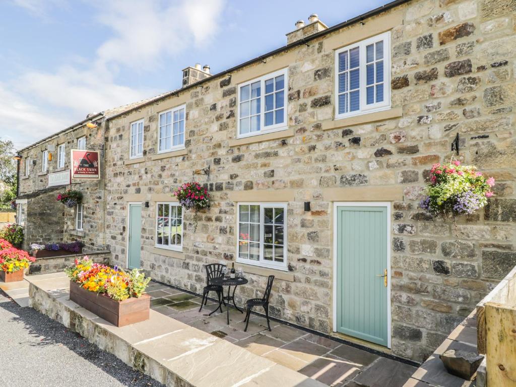 an old stone building with a blue door and windows at Swan Cottage in Fearby