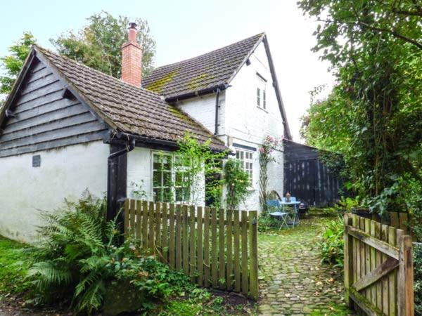 a small white house with a wooden fence at The Smithy in Leominster