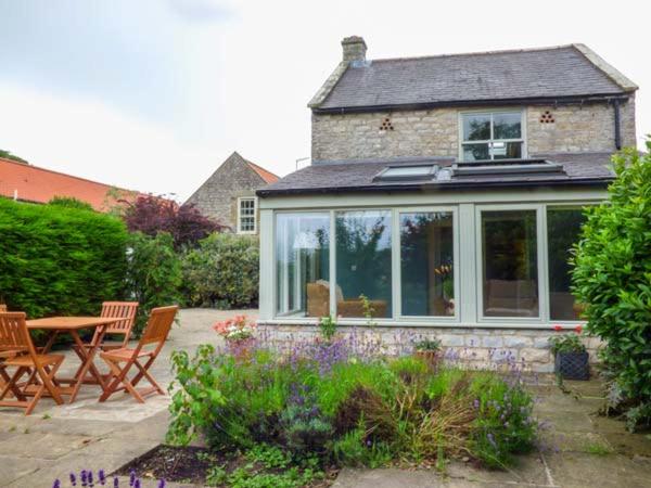 a house with a conservatory with a table and chairs at The Granary in Appleton le Moors