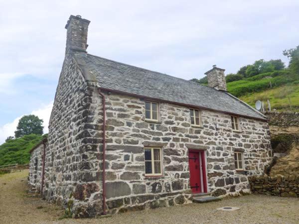 an old stone house with a red door at Tyn Llwyn in Dolgellau
