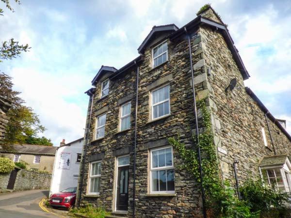 een oud stenen huis met een auto ervoor geparkeerd bij Loughrigg View in Ambleside