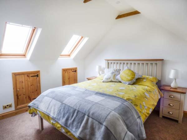 a bedroom with a bed with yellow sheets and windows at Fern Cottage in Heacham
