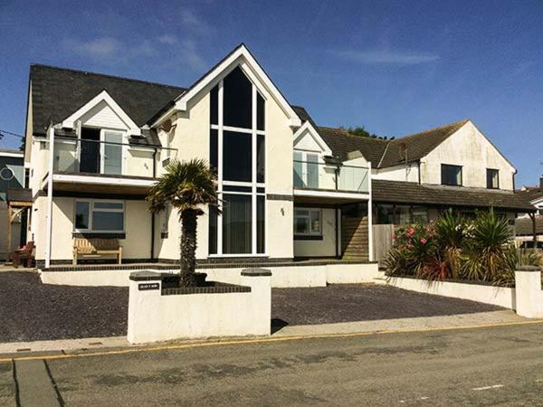 a white house with a palm tree in front of it at Glan Y Mor in Amlwch